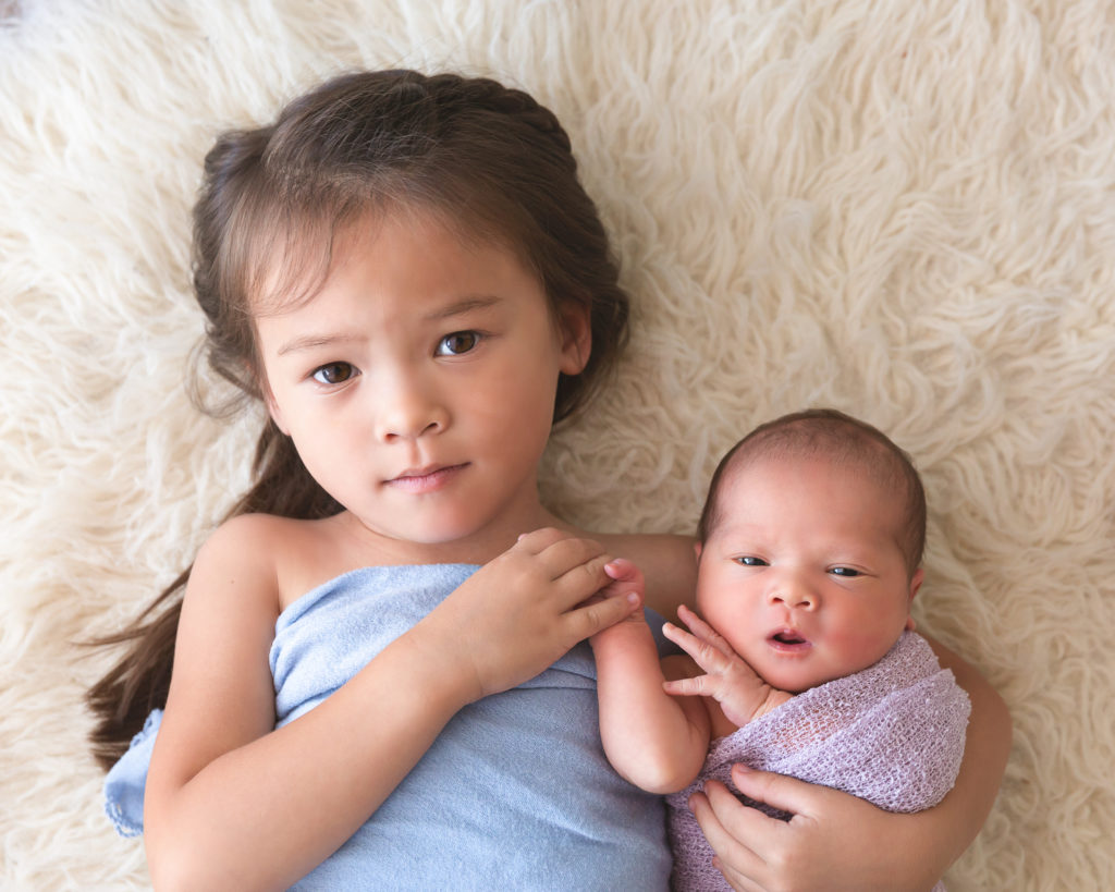 5 year old girl holding baby sister