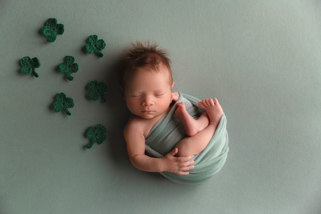 newborn baby wrapped in green with shamrocks around him
