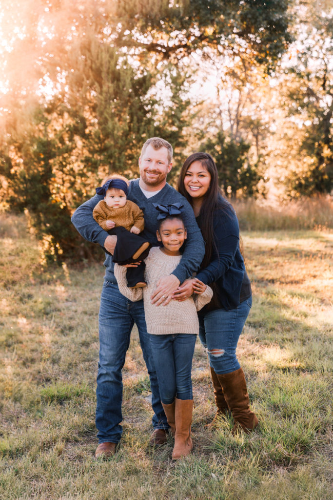 a family with a young girl and baby girl smiling together