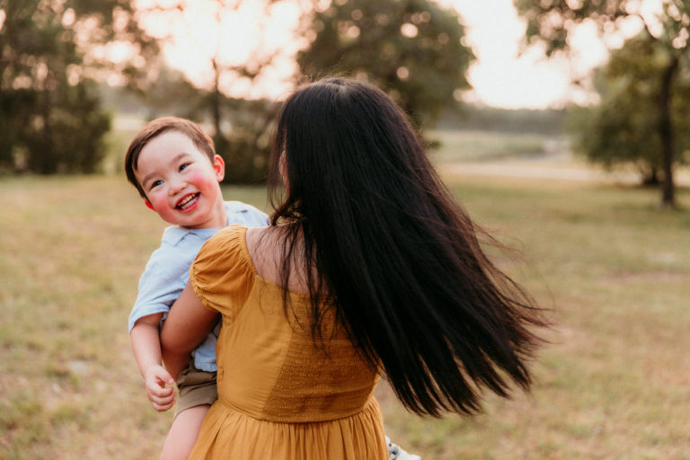 momma spinning aroun with her little boy while he laughs