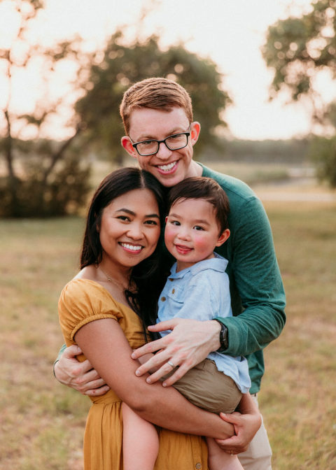 man hugging his wife and toddler boy