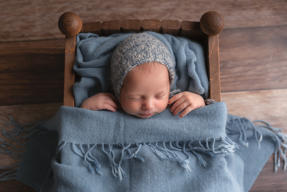 newborn baby boy in little wooden bed