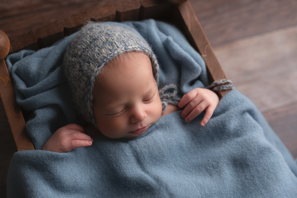 newborn baby boy in little wooden bed