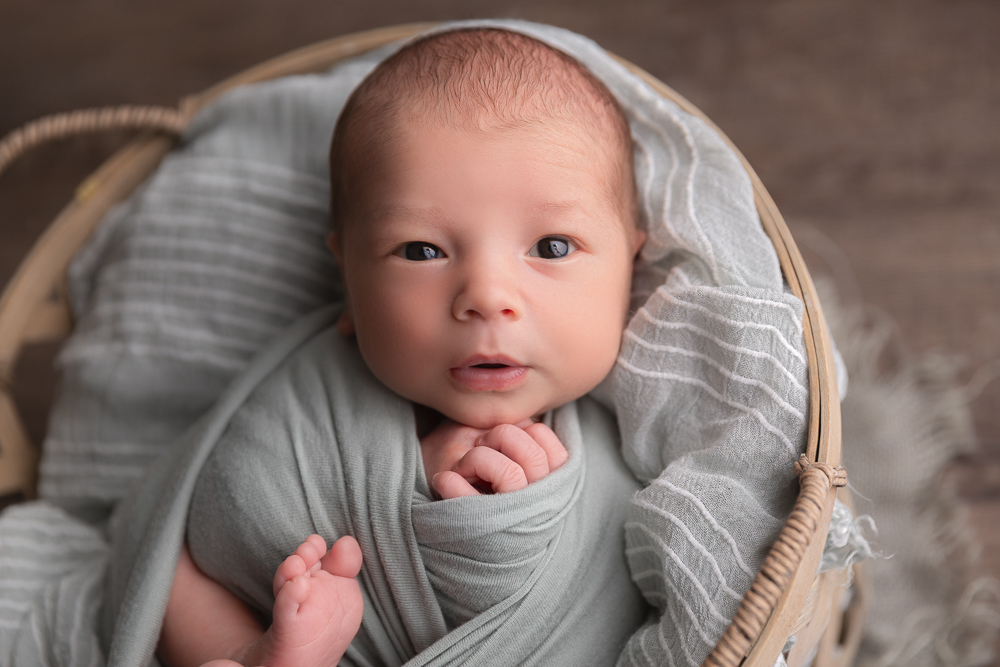 a newborn awake in a basket and looking at camera