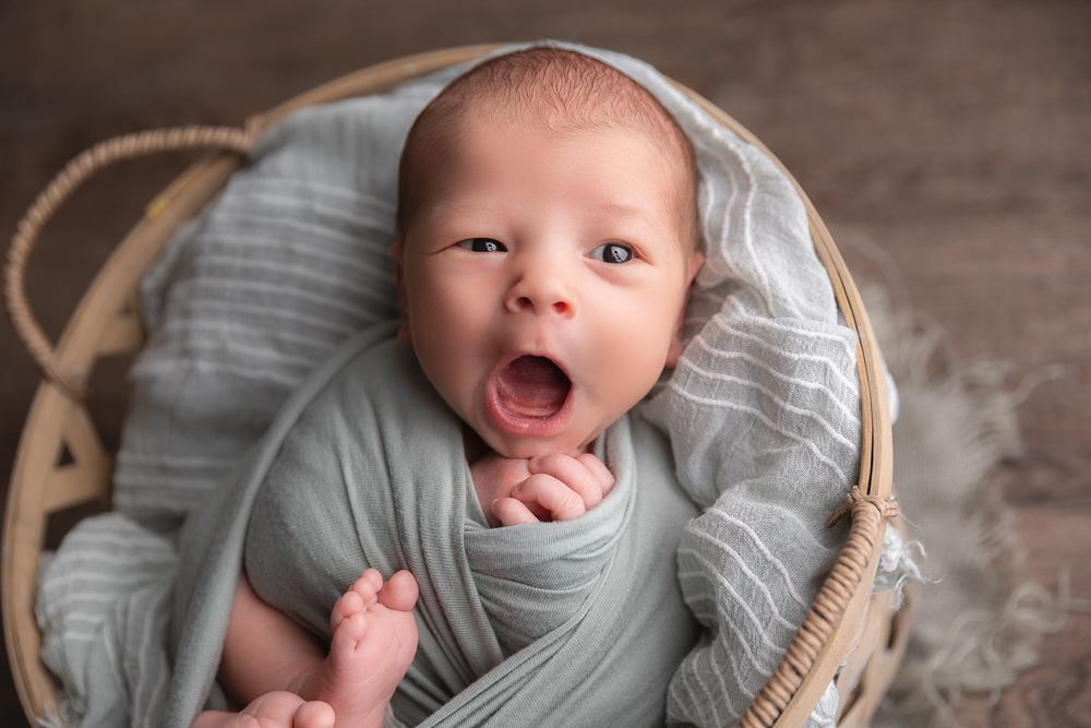 newborn in a basket yawning