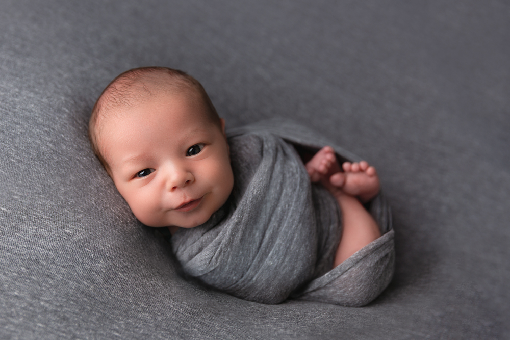 calm baby with eyes open on a gray blanket