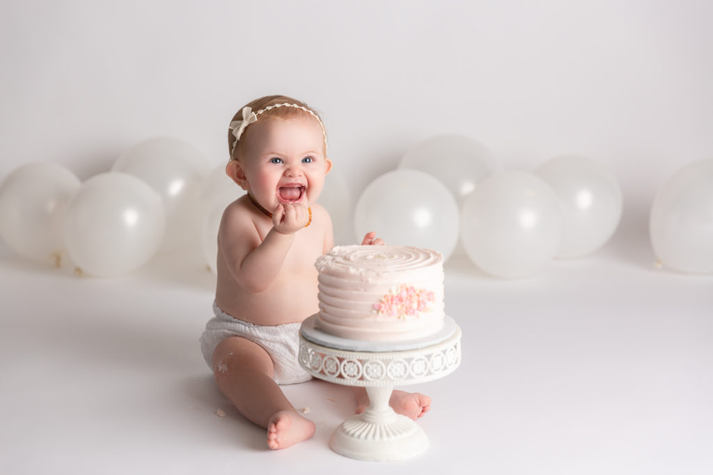 baby with white balloons and birthday cake