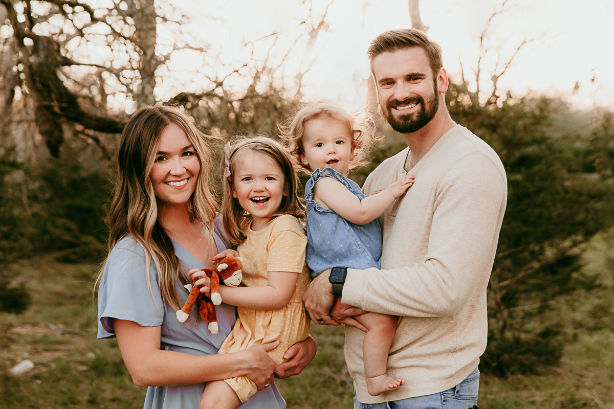 mom and dad and two little girl smiling at the camera